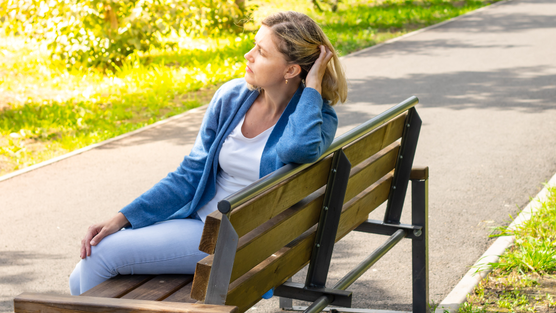 Woman sitting on a park bench overwhelmed by her mental health diagnosis